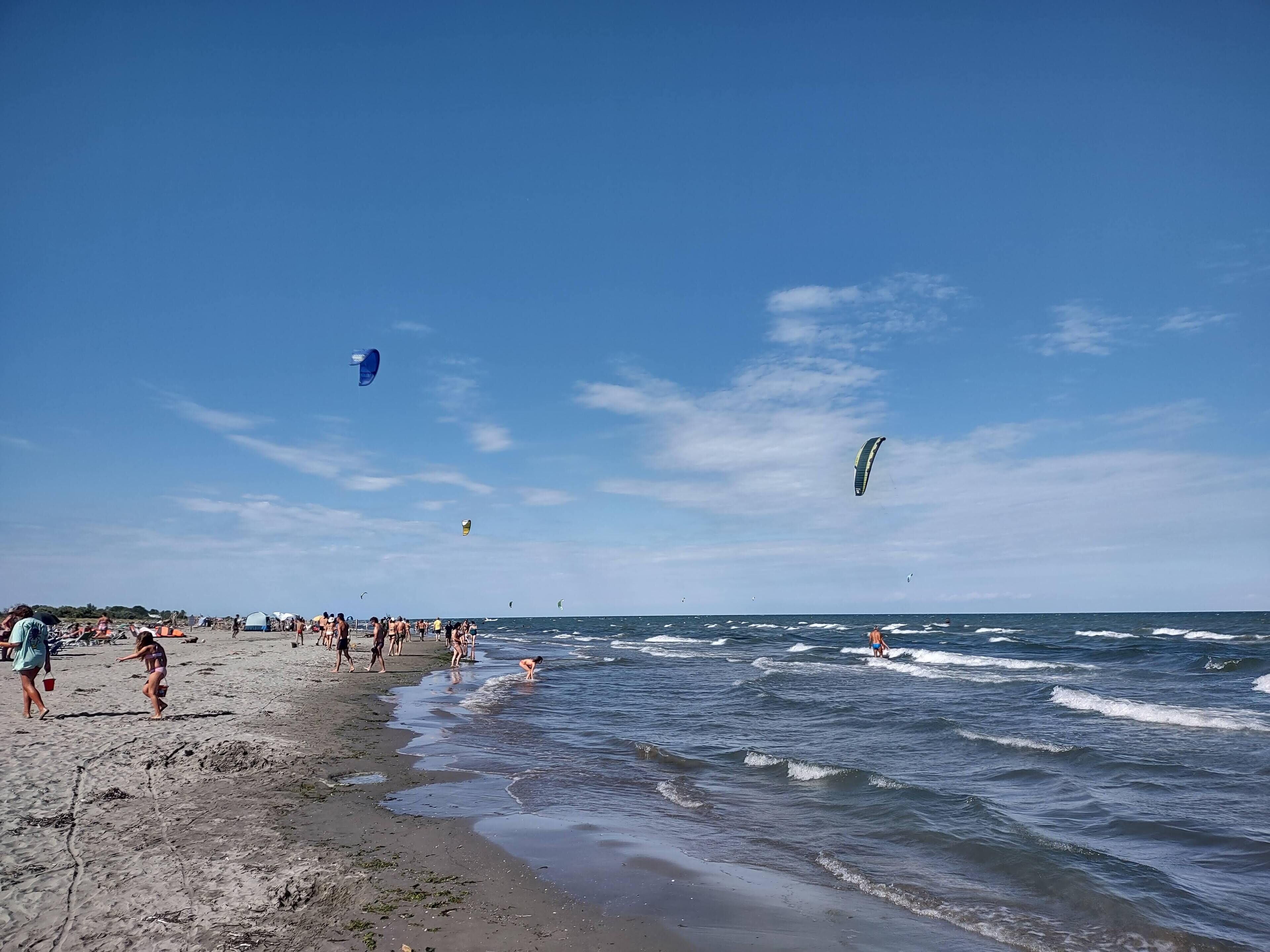 Une plage avec des gens, des tentes et des cerfs-volants.