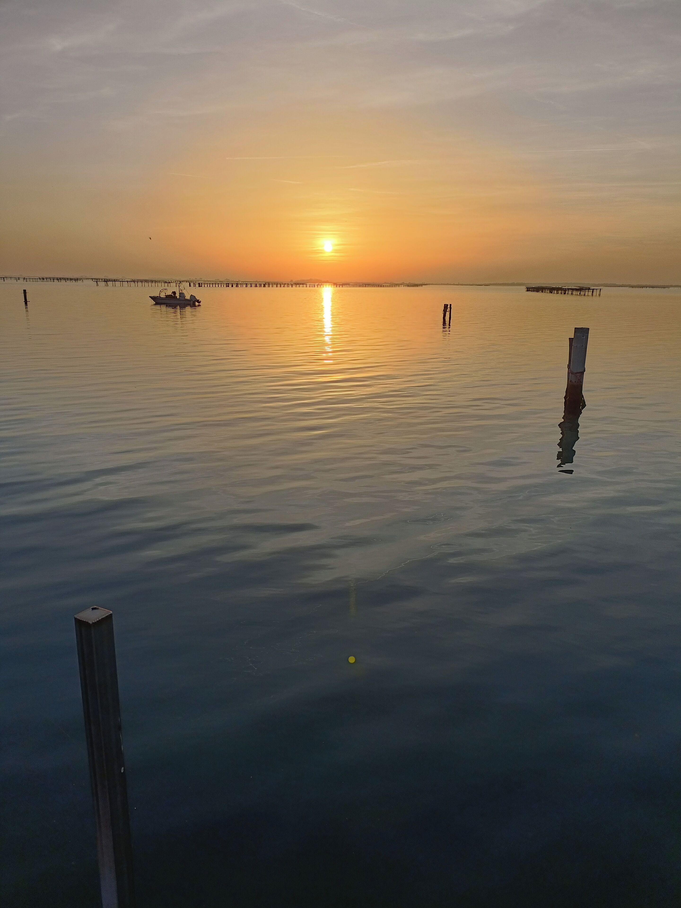 A calm body of water at sunset with a pier extending into it.