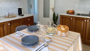 A kitchen with a striped tablecloth, wooden cabinets, a coffee maker, and a bowl of fruit. - The Yellow House (Scardovari)