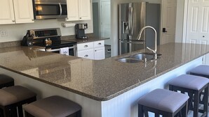 A modern kitchen with white cabinetry, stainless steel appliances, and a granite countertop. - Lakefront escape! Boat Dock, Fishing, Kayaks! Near Hiking, Wineries, Marinas!! (Creal Springs)
