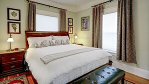 Un dormitorio ordenado con una cama grande, una mesita de noche con una lámpara y un banco.