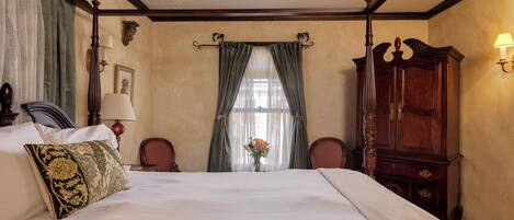 Habitación de hotel con una cama grande, un armario de madera, un escritorio con lámpara y una ventana con cortinas.
