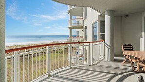 Ein Balkon mit Blick auf den Strand, einem Esstisch und einem Stuhl.
