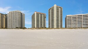 Ein Strandhotel mit mehreren Hochhäusern, Sandstrand und blauem Himmel.
