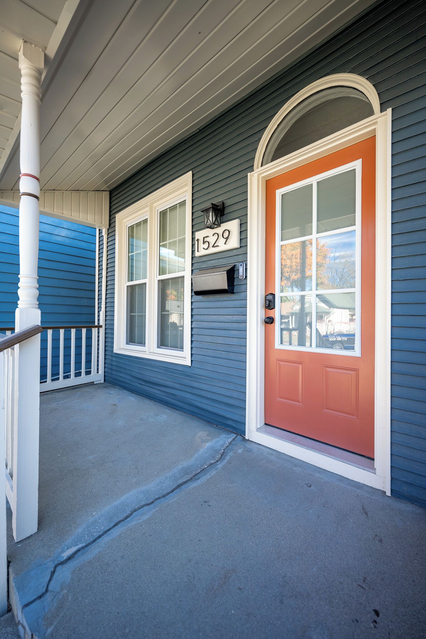 A house with a porch, a red door, and a mailbox with the number 1529.
