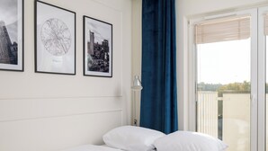 A bedroom with a bed, white bedding, and three framed pictures on the wall. - Praga Bliska Glamour Studio (Warszawa)