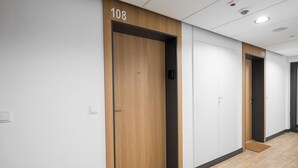A hallway with doors numbered 108 and 109, wooden flooring, and recessed ceiling lights. - Praga Bliska Glamour Studio (Warszawa)