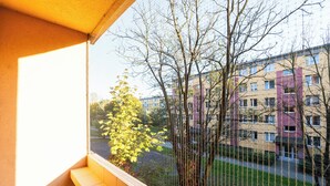 Un balcon donnant sur un immeuble d’habitation et un arbre.