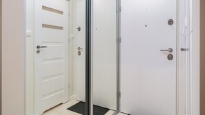 Une pièce avec une porte blanche, une porte en verre et un paillasson noir à l’entrée.