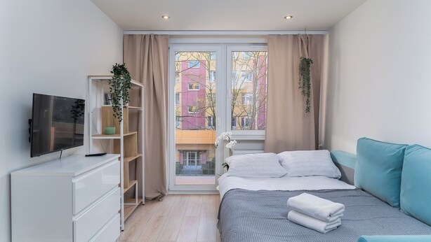 Une chambre moderne avec un lit, une télévision, une commode et une fenêtre avec des rideaux.