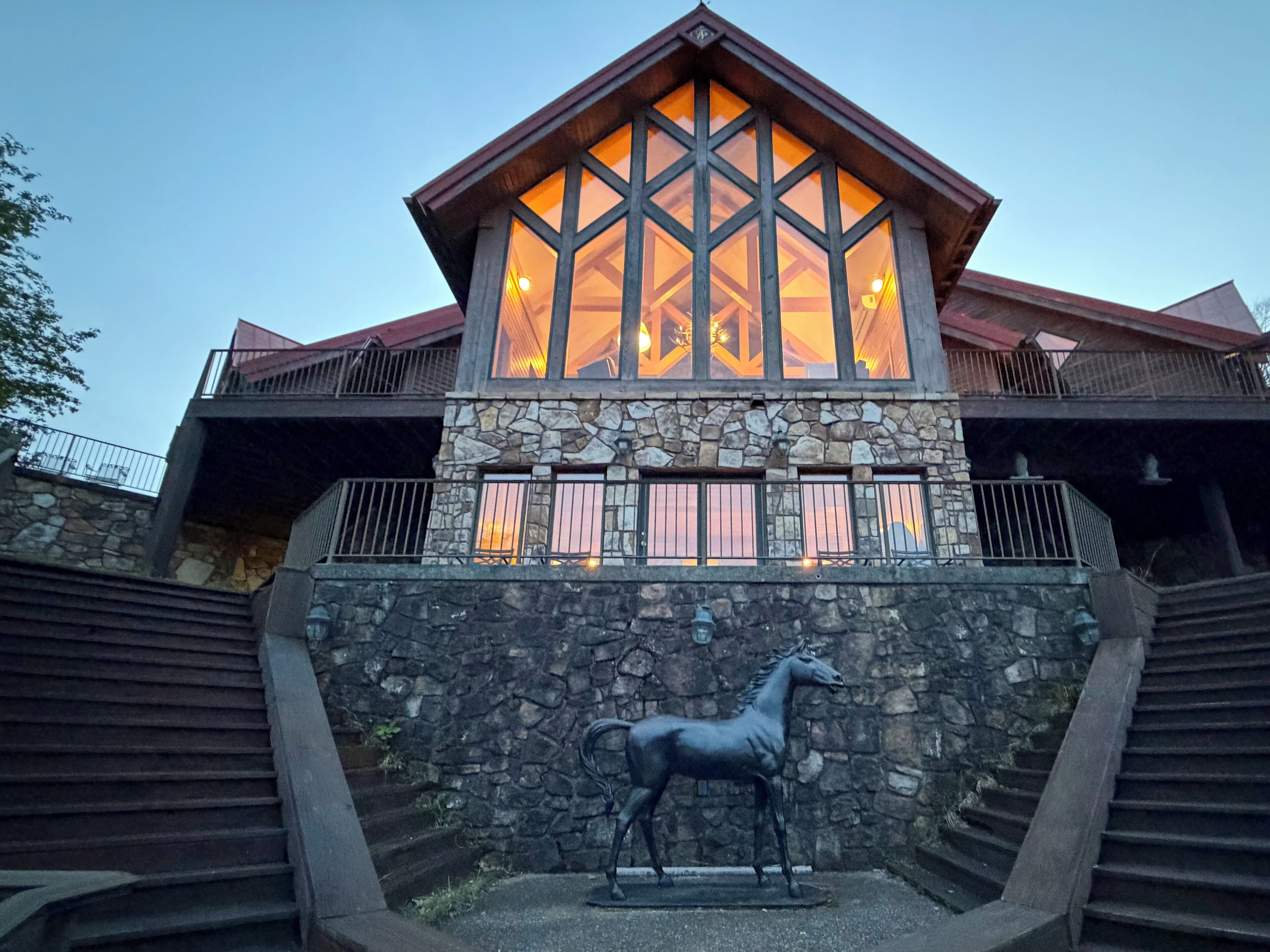 Un edificio con facciata in pietra, ampie finestre e una statua di un cavallo di fronte.