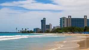 Una playa con vistas a un complejo hotelero al fondo.