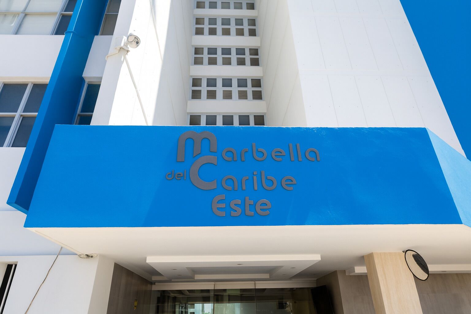 Entrada de hotel con un letrero azul que dice 'Marbella del Caribe Este'.