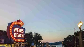 Un panneau indiquant « Weirs Beach », avec une flèche distinctive et des lettres illuminées.