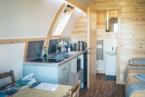 A compact kitchen with a window, a sink, and a small dining area. - Cosy Welsh Cabin with Incredible Views (Knighton)