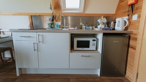A compact kitchen with white cabinets, a built-in microwave, a refrigerator, and a window above the sink.