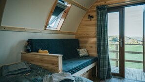 A cozy bedroom with a bunk bed, a small desk, and a window overlooking a scenic landscape.