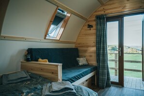 A cozy bedroom with a bunk bed, a small desk, and a window overlooking a scenic landscape.