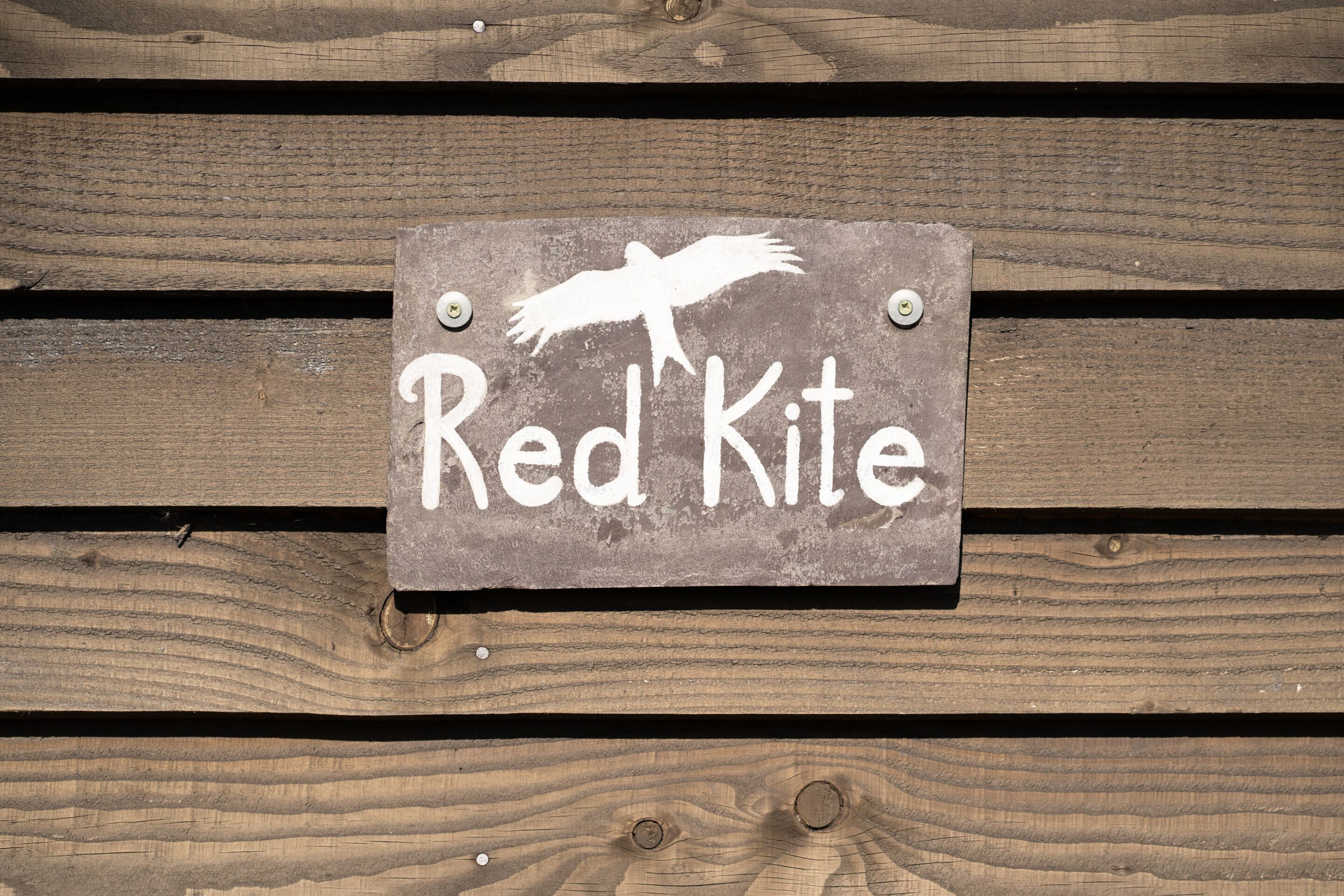 A wooden sign with the text "Red Kite" and a silhouette of a kite.