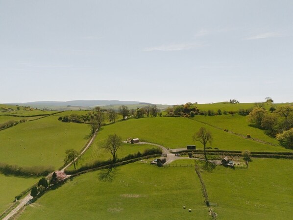 Eine ländliche Landschaft mit sanften, grünen Hügeln, einer gewundenen Straße und verstreuten Bauernhäusern.