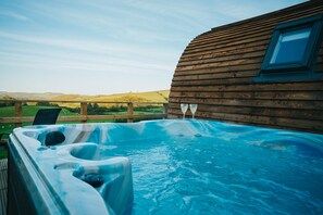 Un bain à remous avec une terrasse en bois et une vue sur la campagne.