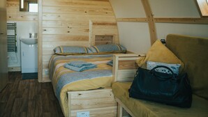 A cozy, wooden-paneled room with a bed, a small bathroom, and a window. - Rural Welsh Cabin with Spectacular Views (Knighton)