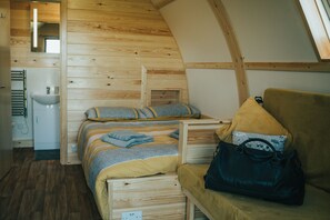 Una habitación acogedora con paneles de madera, una cama, un baño pequeño y una ventana.