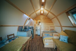 A compact, wood-paneled room with a loft bed, a small kitchenette, and a dining area.