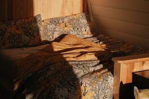 Un lit avec une literie à motifs et une table de chevet en bois.
