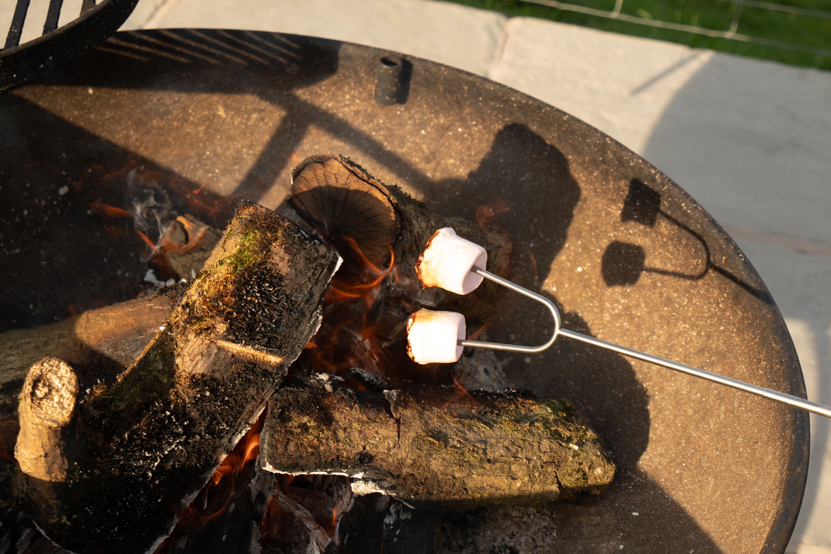 En lägereld med ved och en marshmallows på en pinne.