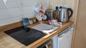 Ett kompakt kök med en inbyggd induktionshäll, en mikrovågsugn, en kaffebryggare och en brödrost.