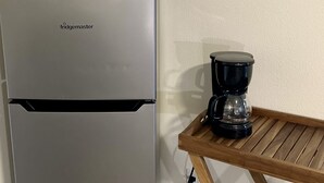 Ett köksutrymme med ett kylskåp från Frigidaire, en kaffebryggare på ett träbord och en inramad affisch med temat ”Havsfåglar” på väggen.