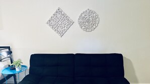 En svart soffa, ett litet blått bord med en växt och två väggdekorationer.