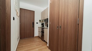 Een smalle gang met houten deuren en een keuken met kasten en apparatuur.