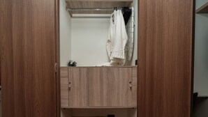Een houten garderobe met een kledingroede en een mand eronder.