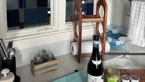 A kitchen with a blue countertop, a wine bottle, and a wooden chair. - Perfect Work Retreat on Market St. Downtown ILM (Wilmington)