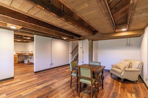 Un comedor con mesa y sillas de madera, un sofá a cuadros y una escalera que conduce a otra habitación.
