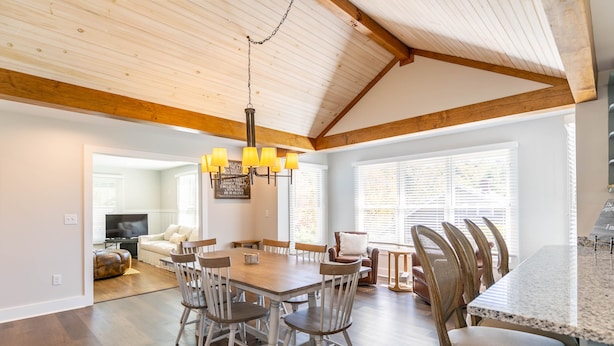 Un comedor espacioso con una mesa y sillas de madera, un candelabro y una cocina con encimera de granito.