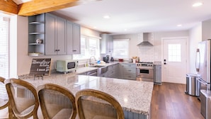 Una cocina moderna con armarios grises, encimera de granito y una isla central con sillas.