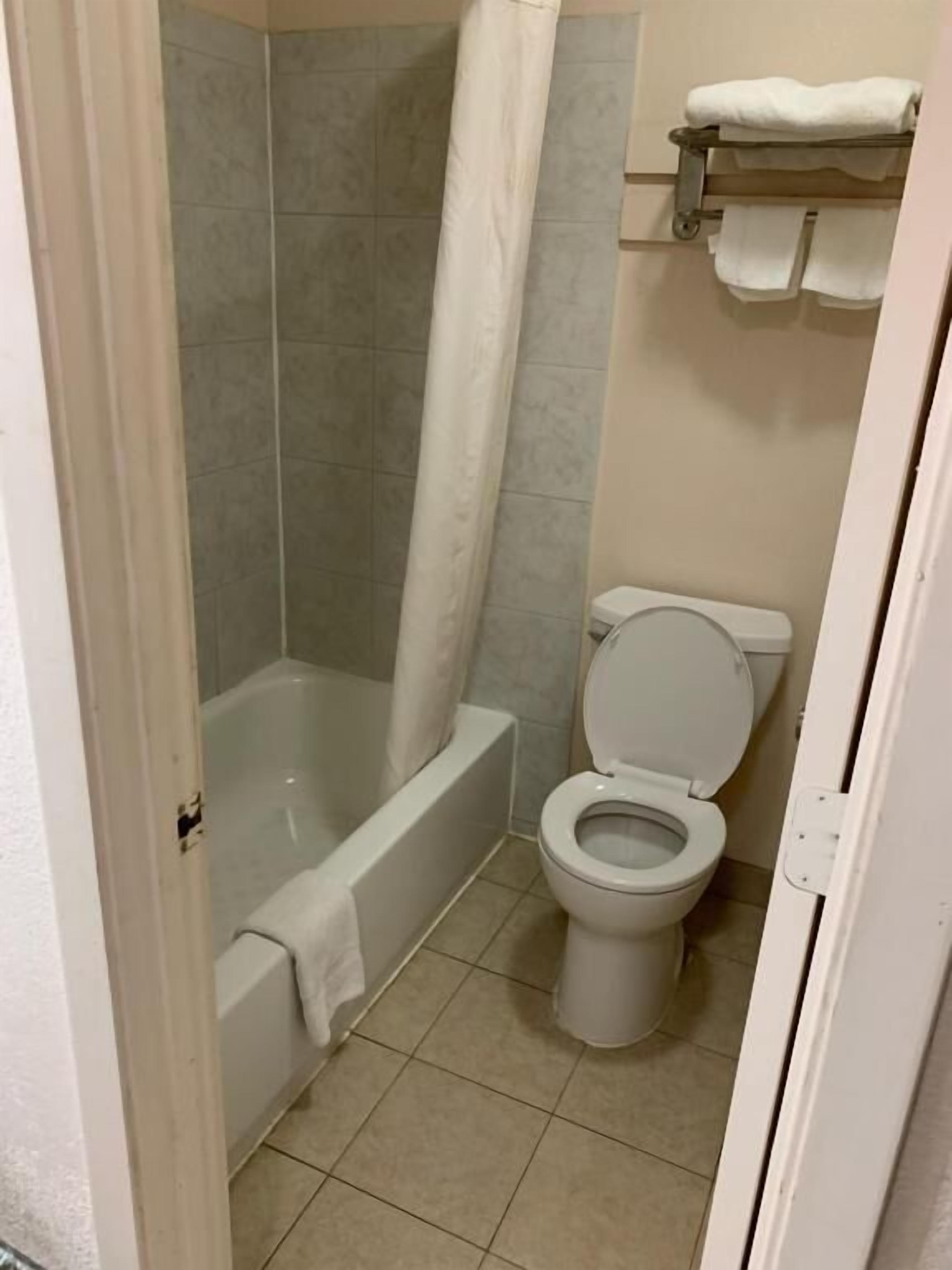 A bathroom with a bathtub, toilet, and shower curtain.