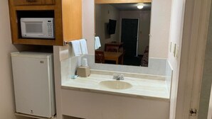 A compact kitchen with a microwave, a sink, and a small refrigerator. - Regency Inn (Jewett)