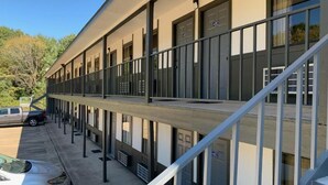 A multi-story motel with a central corridor, individual rooms on either side, and a parking area in front. - Regency Inn (Jewett)