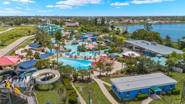 Ein Wasserpark mit mehreren Rutschen und Pools, umgeben von viel Grün und einem See.