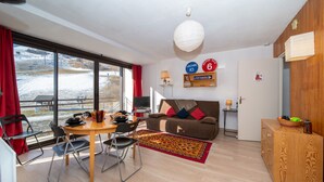 A modern living room with a dining area, large windows, and a view of a snowy landscape. - Baikonour by Interhome (Le Corbier)