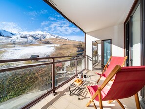 Een balkon met uitzicht op een besneeerd landschap en bergen.