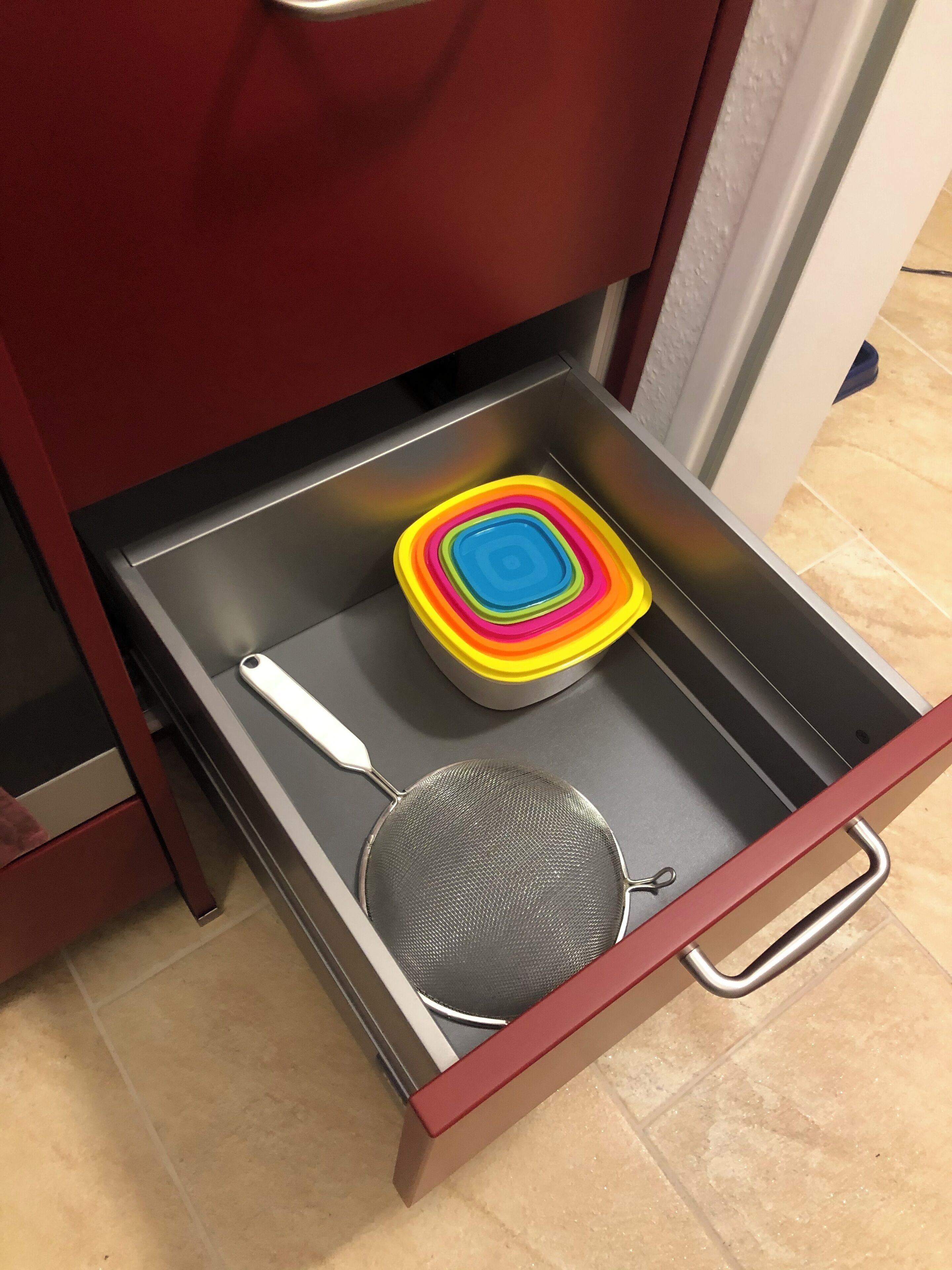 A drawer with a colorful container and a strainer.