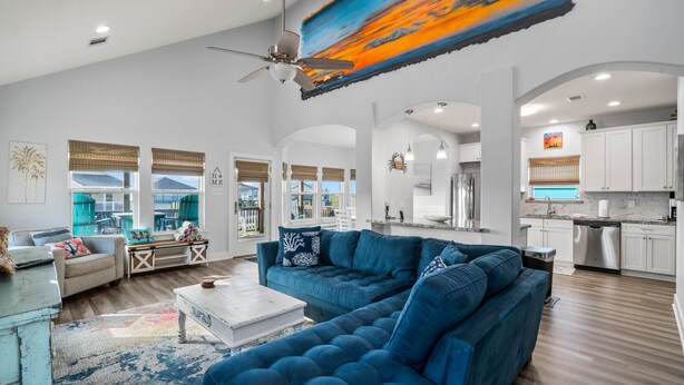 A spacious living room with a large blue sofa, a white coffee table, and a view of the outside.