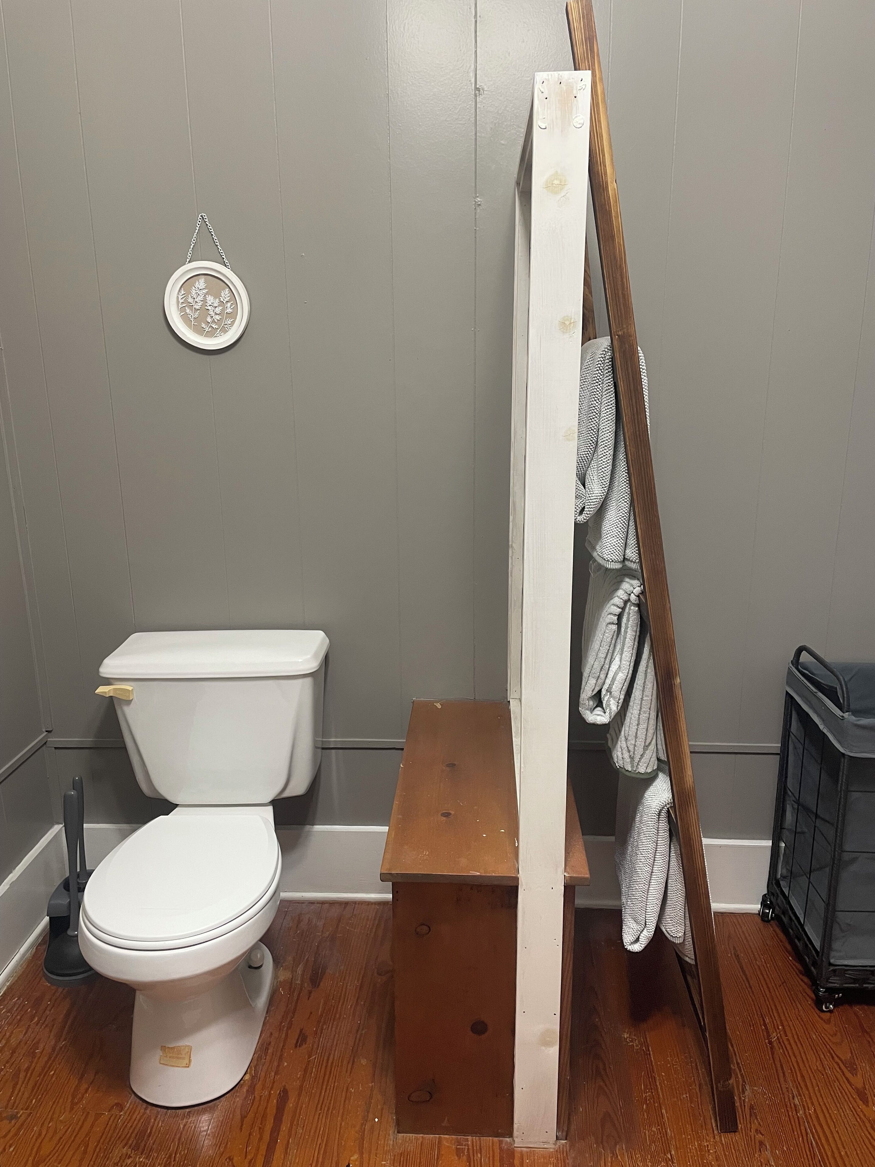 Ein Badezimmer mit Toilette, einer Holzbank und einem Handtuchhalter.