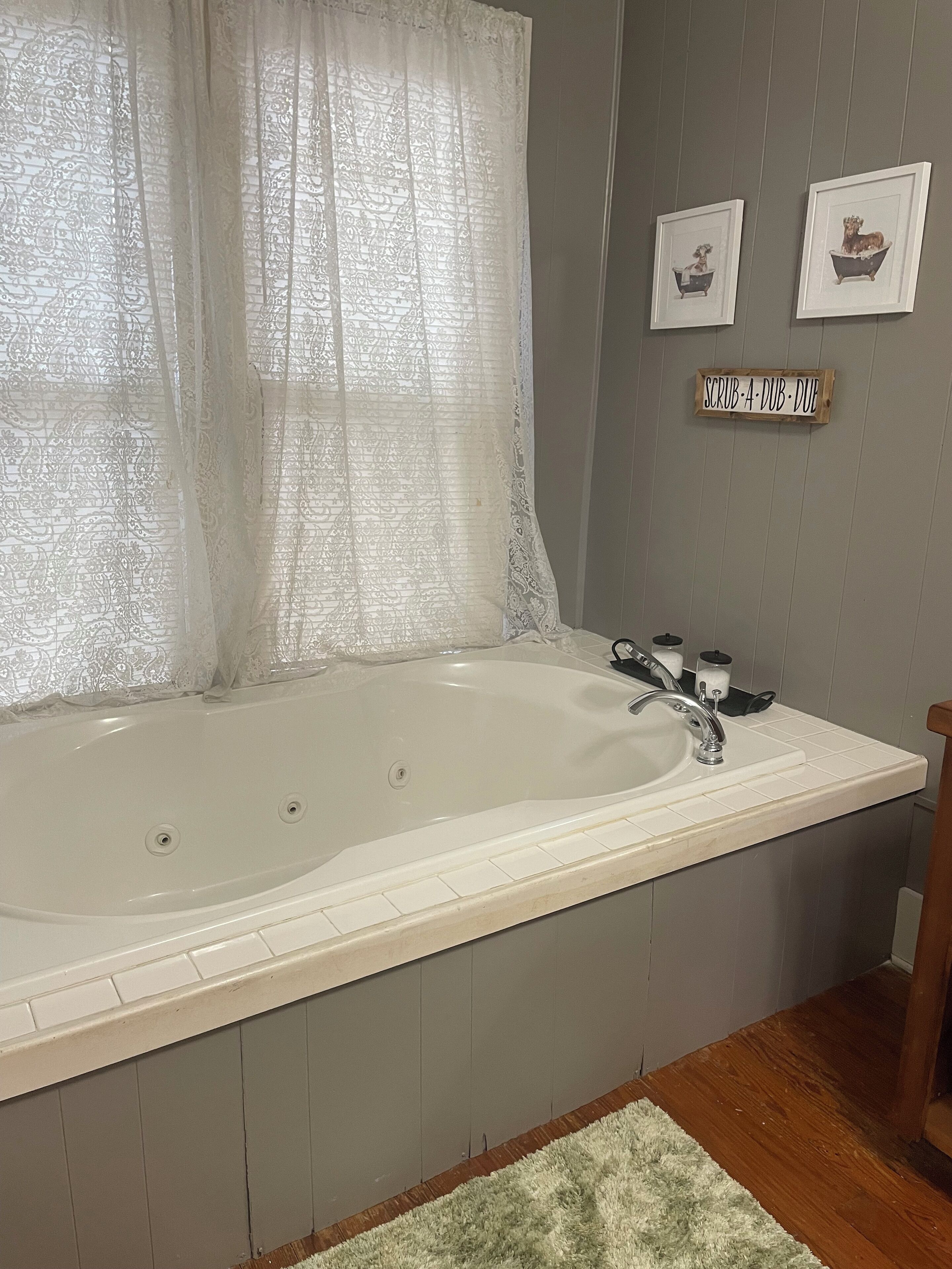 Une salle de bain avec une grande baignoire, un lavabo et un plancher en bois.