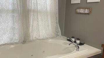 Une salle de bain avec une grande baignoire, un lavabo et un plancher en bois.